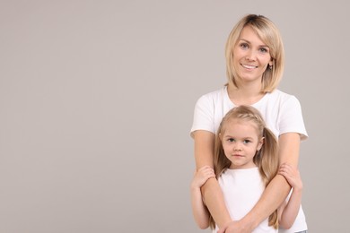 Family portrait of happy mother and daughter on grey background. Space for text