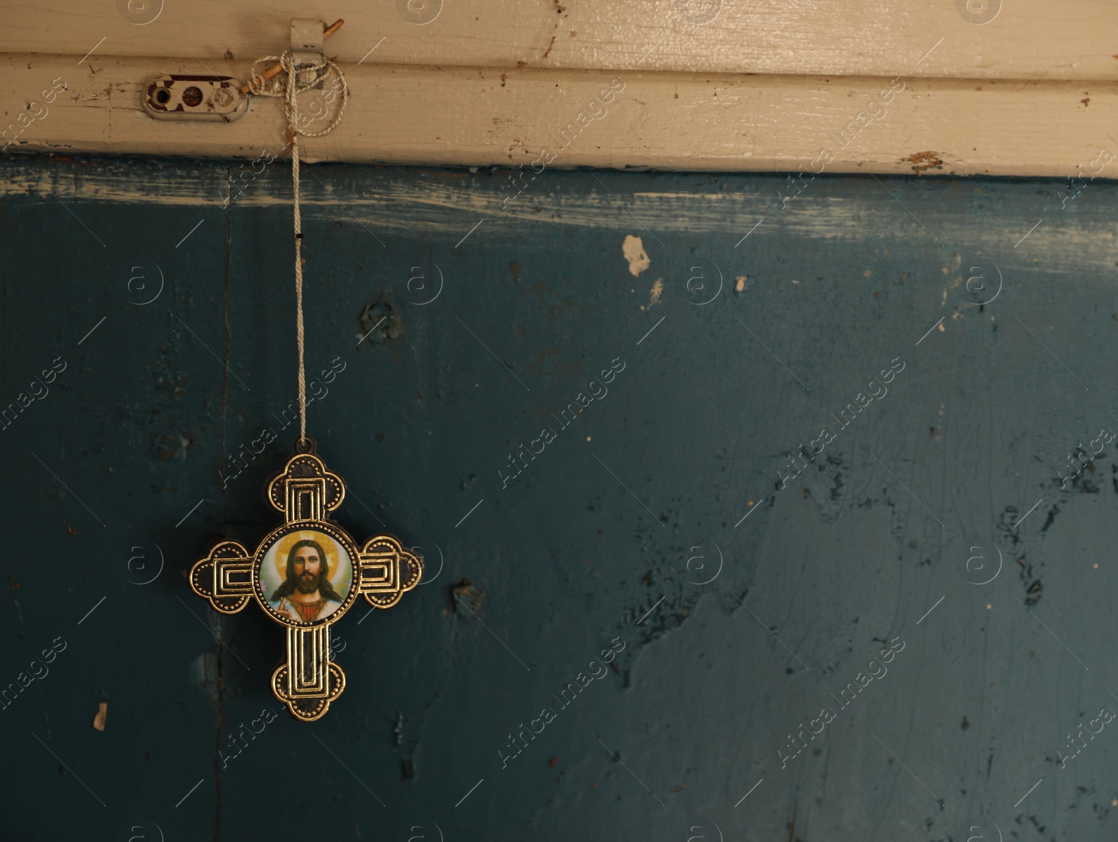 Photo of Cross with icon hanging on blue wall indoors, space for text