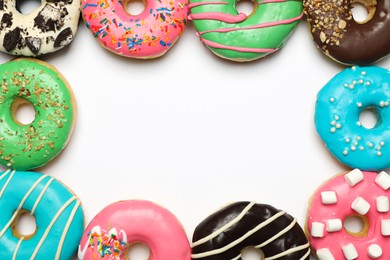 Photo of Different delicious glazed doughnuts on white background, top view. Space for text