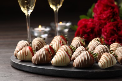 Photo of Delicious chocolate covered strawberries, sparkling wine and flowers on wooden table