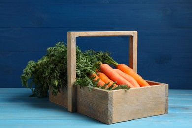 Fresh ripe juicy carrots in basket on light blue wooden table