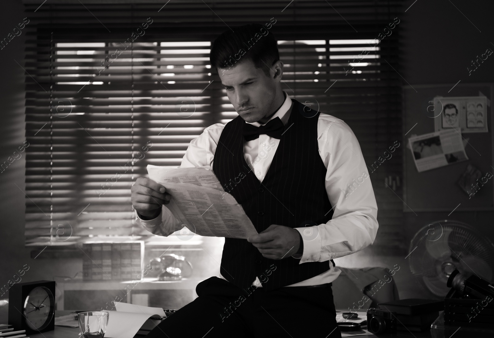 Photo of Old fashioned detective with documents in office. Black and white effect