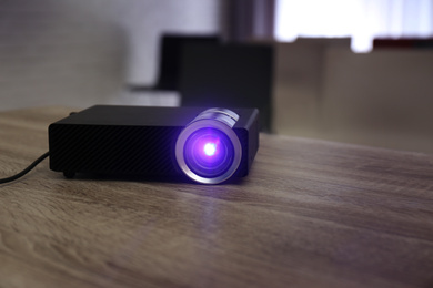 Photo of Modern video projector on wooden table in conference room