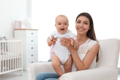 Photo of Young mother with her cute baby girl in armchair at home