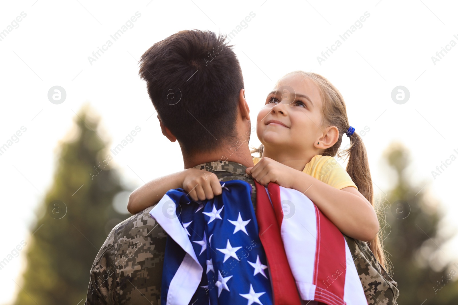 Photo of Father in military uniform with American flag and his daughter at sunny park