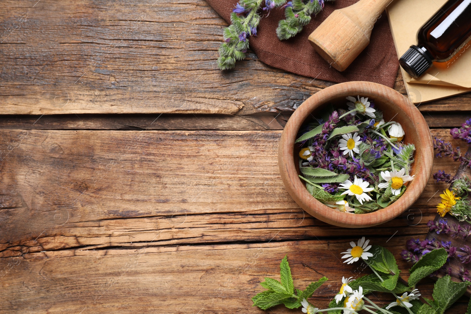 Photo of Flat lay composition with mortar and different healing  herbs on wooden table, space for text