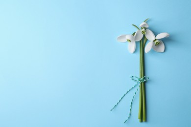 Beautiful snowdrops on light blue background, flat lay. Space for text