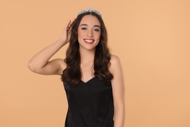 Photo of Beautiful young woman with tiara in stylish dress on beige background