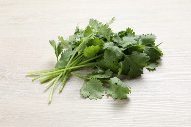 Photo of Bunch of fresh aromatic cilantro on white wooden table