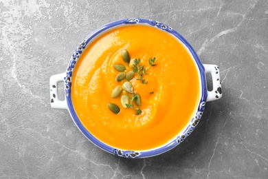 Photo of Delicious pumpkin soup in bowl on marble table, top view