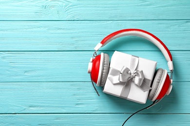 Photo of Flat lay composition with gift box and headphones on wooden background. Christmas music concept