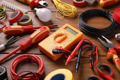 Set of electrician's tools and accessories on wooden background