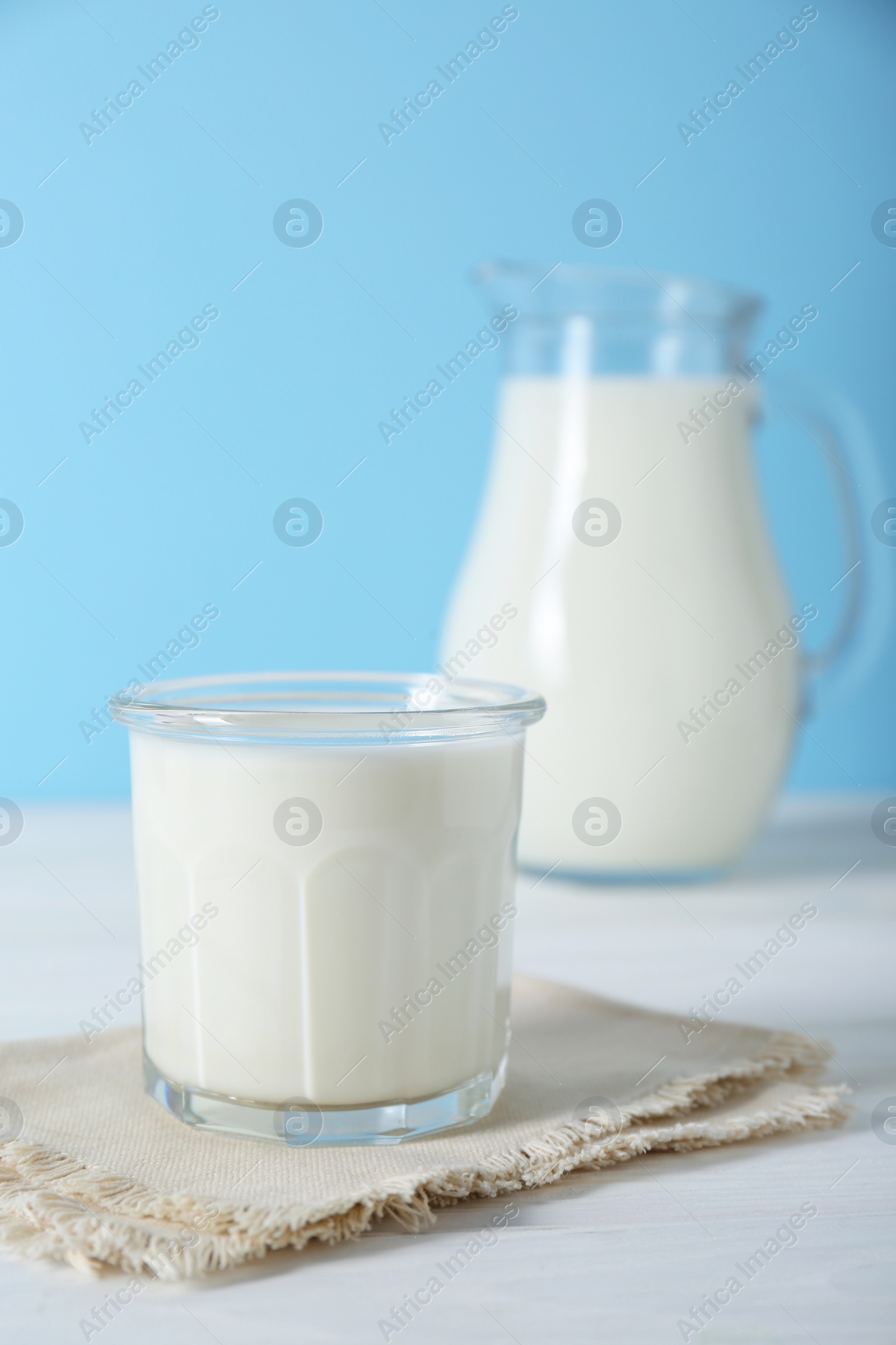 Photo of Glass of fresh milk and jug on white wooden table