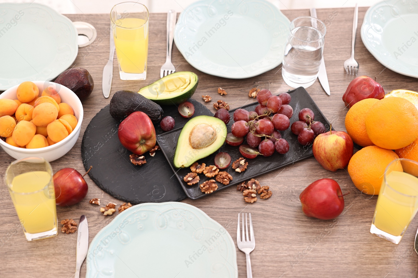 Photo of Healthy vegetarian food, glasses of juice, plates and cutlery on wooden table