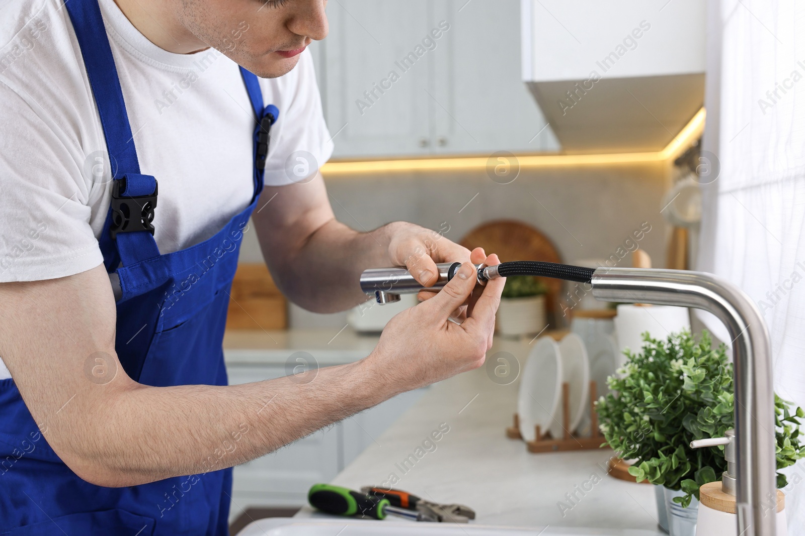 Photo of Plumber examining metal faucet in kitchen, closeup