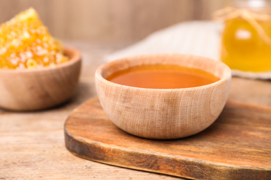 Tasty aromatic honey in bowl on wooden table