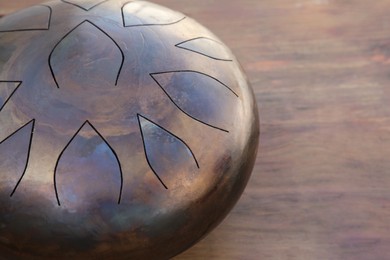 Photo of Steel tongue drum on wooden table, closeup. Space for text. Percussion musical instrument