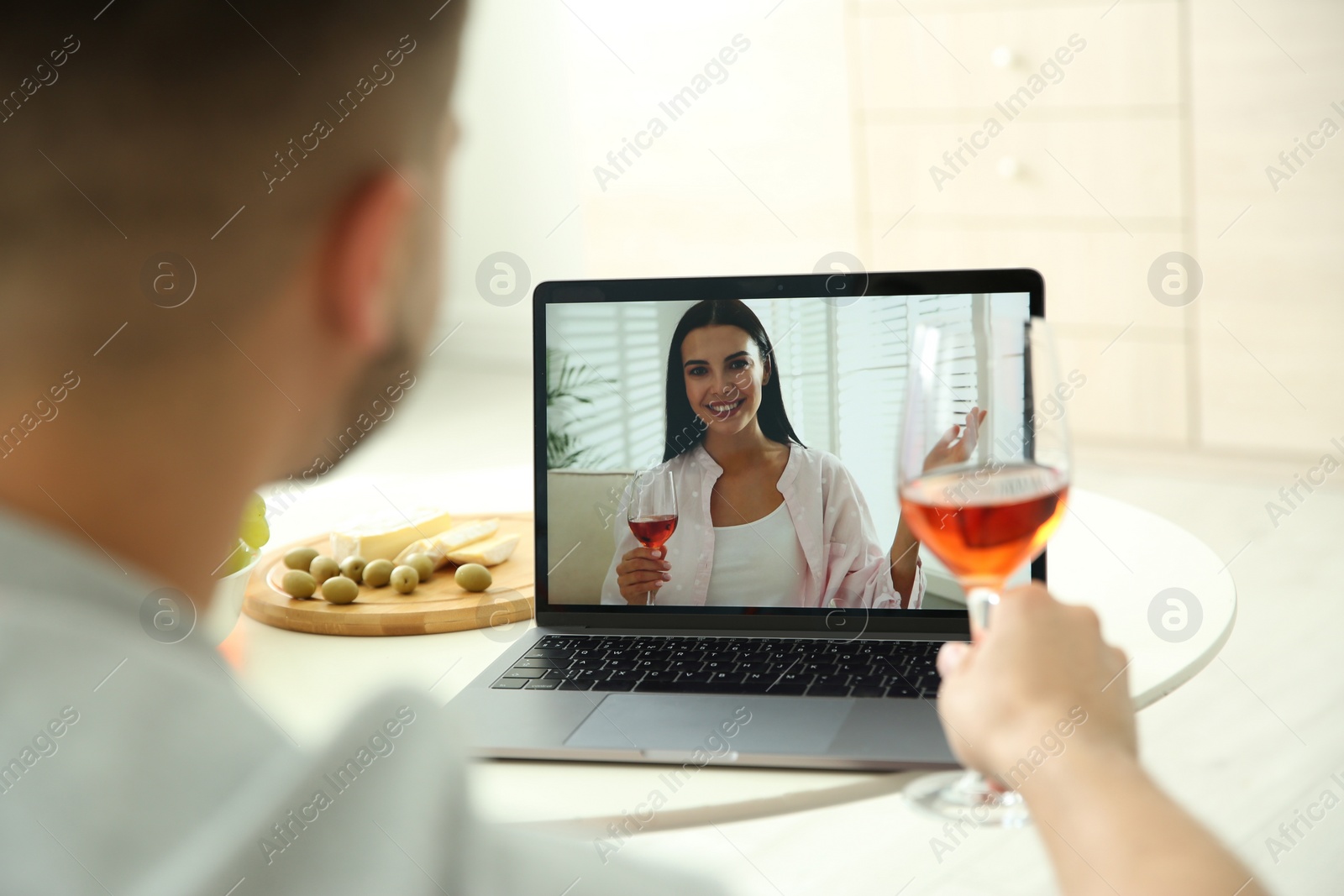 Photo of Friends drinking wine while communicating through online video conference at home. Social distancing during coronavirus pandemic