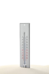 Weather thermometer in sand against white background