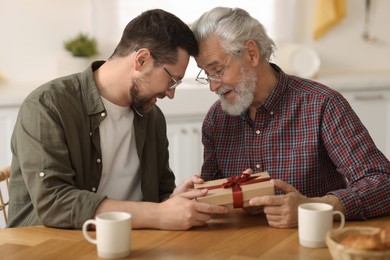 Photo of Son giving gift box to his dad at home