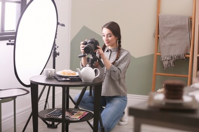 Photo of Young woman with professional camera taking food photo in studio