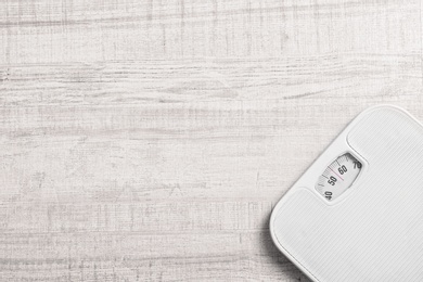 Bathroom scales and space for text on wooden background, top view. Weight loss concept