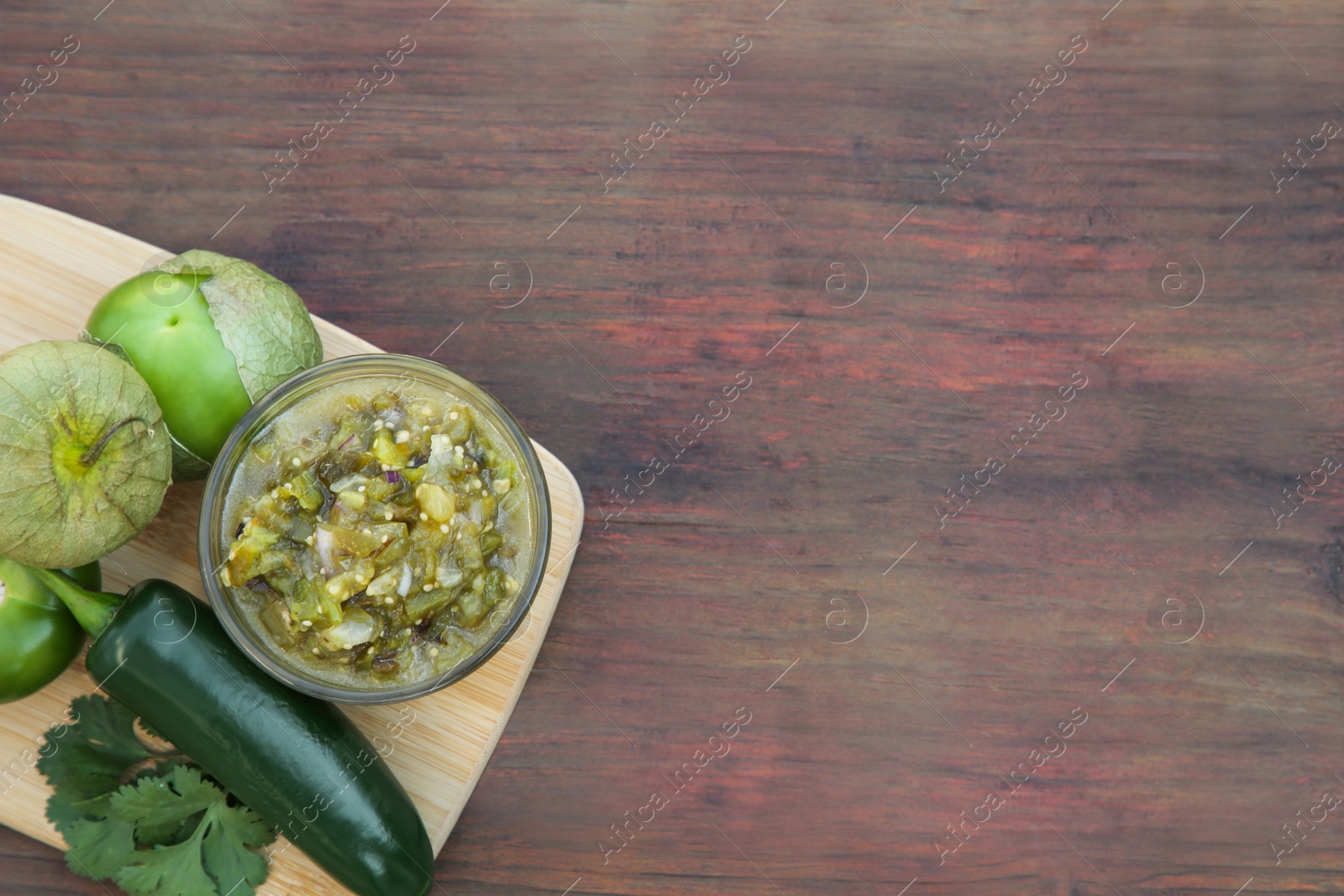 Photo of Tasty salsa sauce and ingredients on wooden table, top view. Space for text