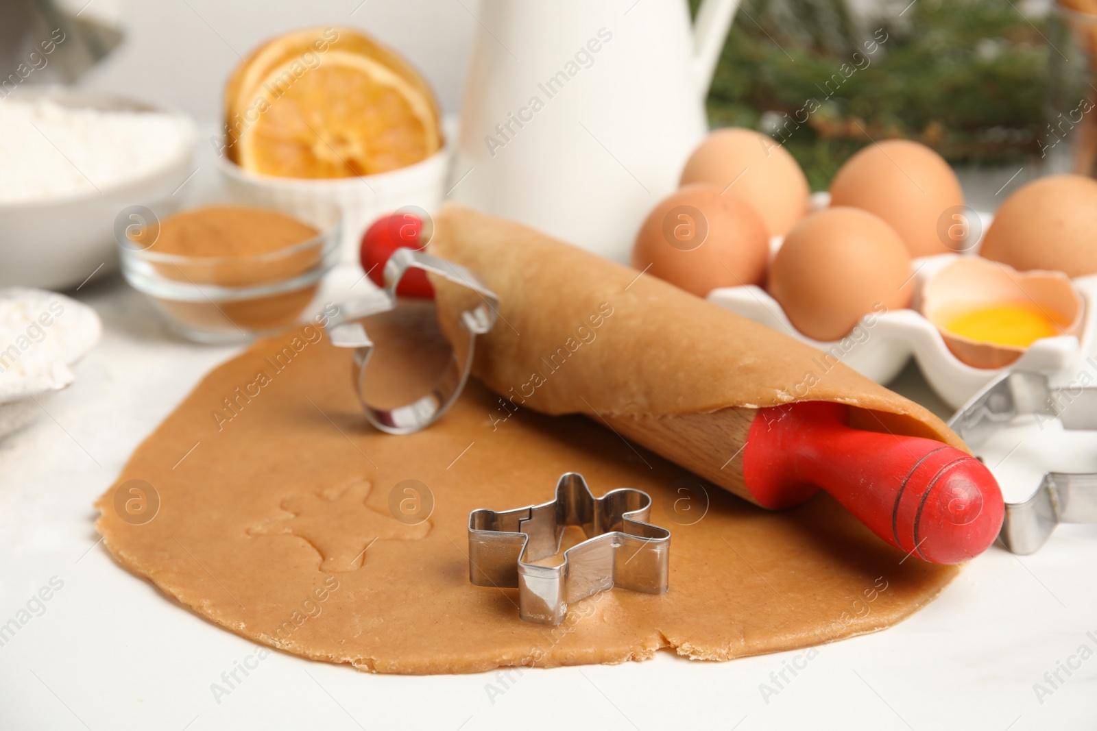 Photo of Cookie cutters, dough and rolling pin on white table. Christmas biscuits