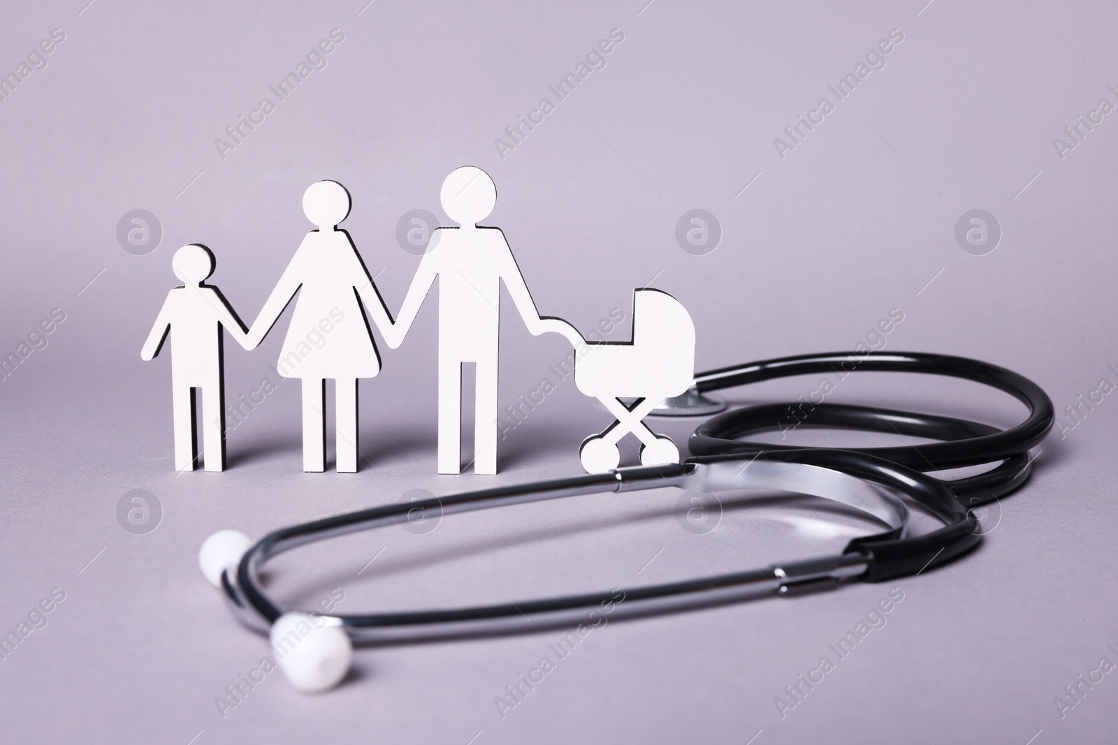 Photo of Figures of family stainding near stethoscope on lilac background. Insurance concept