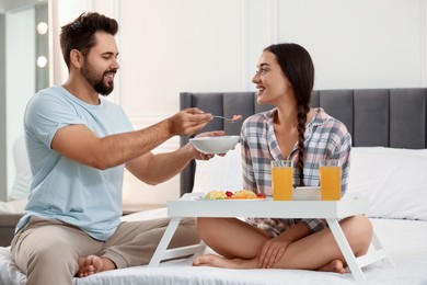 Photo of Happy couple having breakfast on bed at home