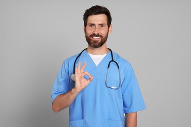 Photo of Doctor with stethoscope showing okay gesture on light grey background