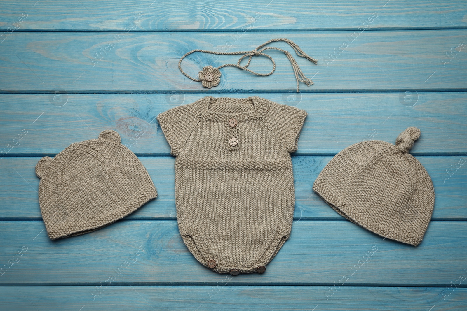 Photo of Set of cute baby knitwear for photoshoot on light blue wooden background, flat lay