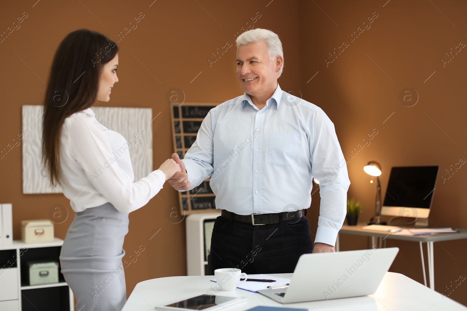 Photo of Human resources manager shaking hands with applicant during job interview in office