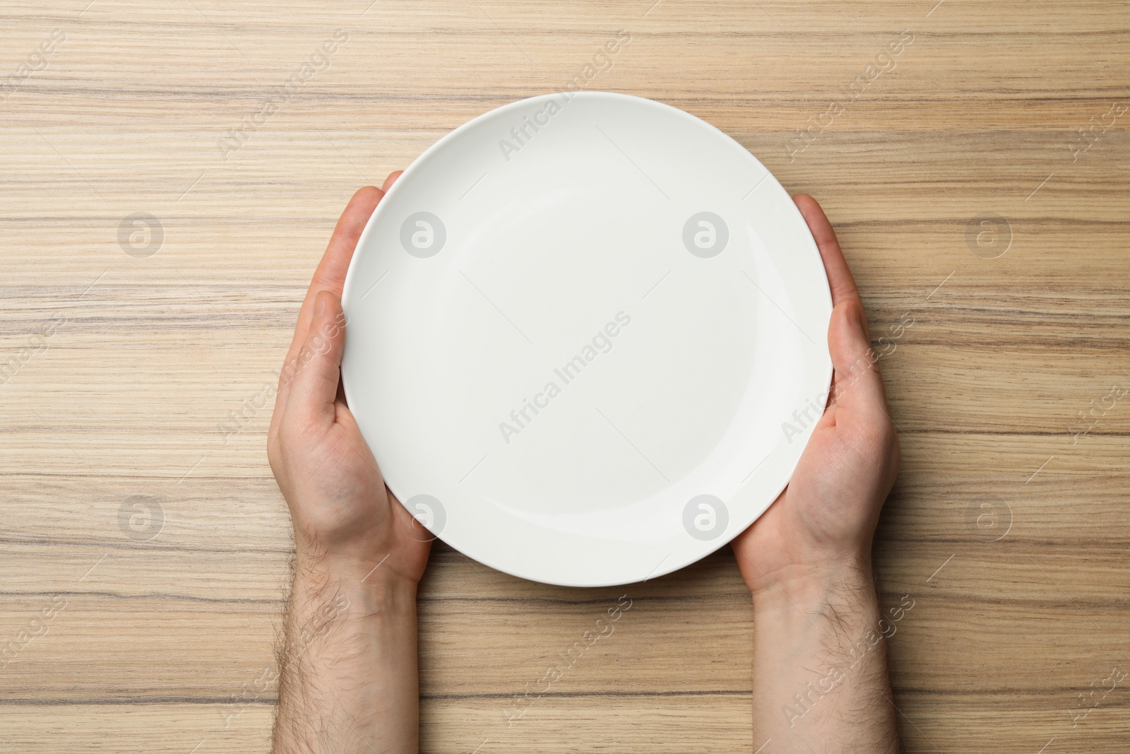 Photo of Man with empty plate at wooden table, top view