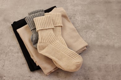 Soft comfortable socks and sweaters on grey table, top view