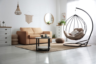 Photo of Stylish leather sofa and swing chair in modern living room interior