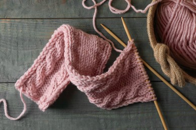 Photo of Soft pink woolen yarn, knitting and needles on wooden table, flat lay