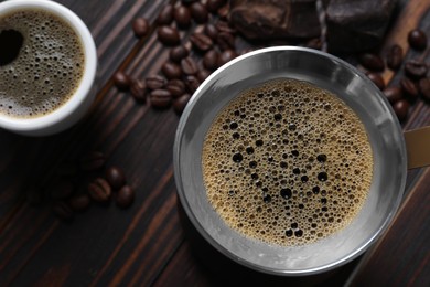 Turkish coffee pot with hot drink and beans on wooden table, flat lay. Space for text