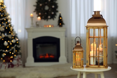 Photo of Christmas lanterns with burning candles in decorated living room. Space for text