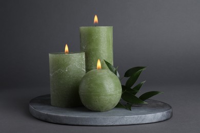 Burning candles with green branch on grey background