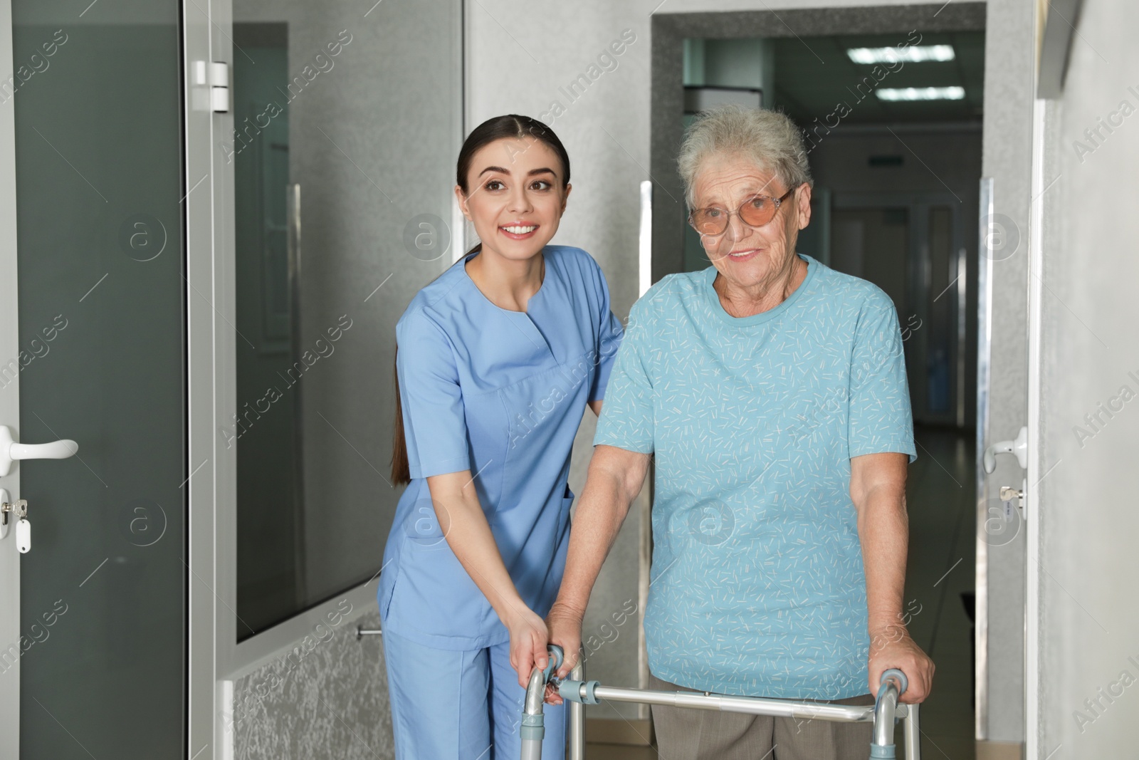 Photo of Nurse assisting senior patient with walker in hospital hallway