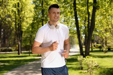 Photo of Young man with headphones on morning run in park. Fitness lifestyle