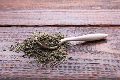 Photo of Spoon with dried thyme on wooden table