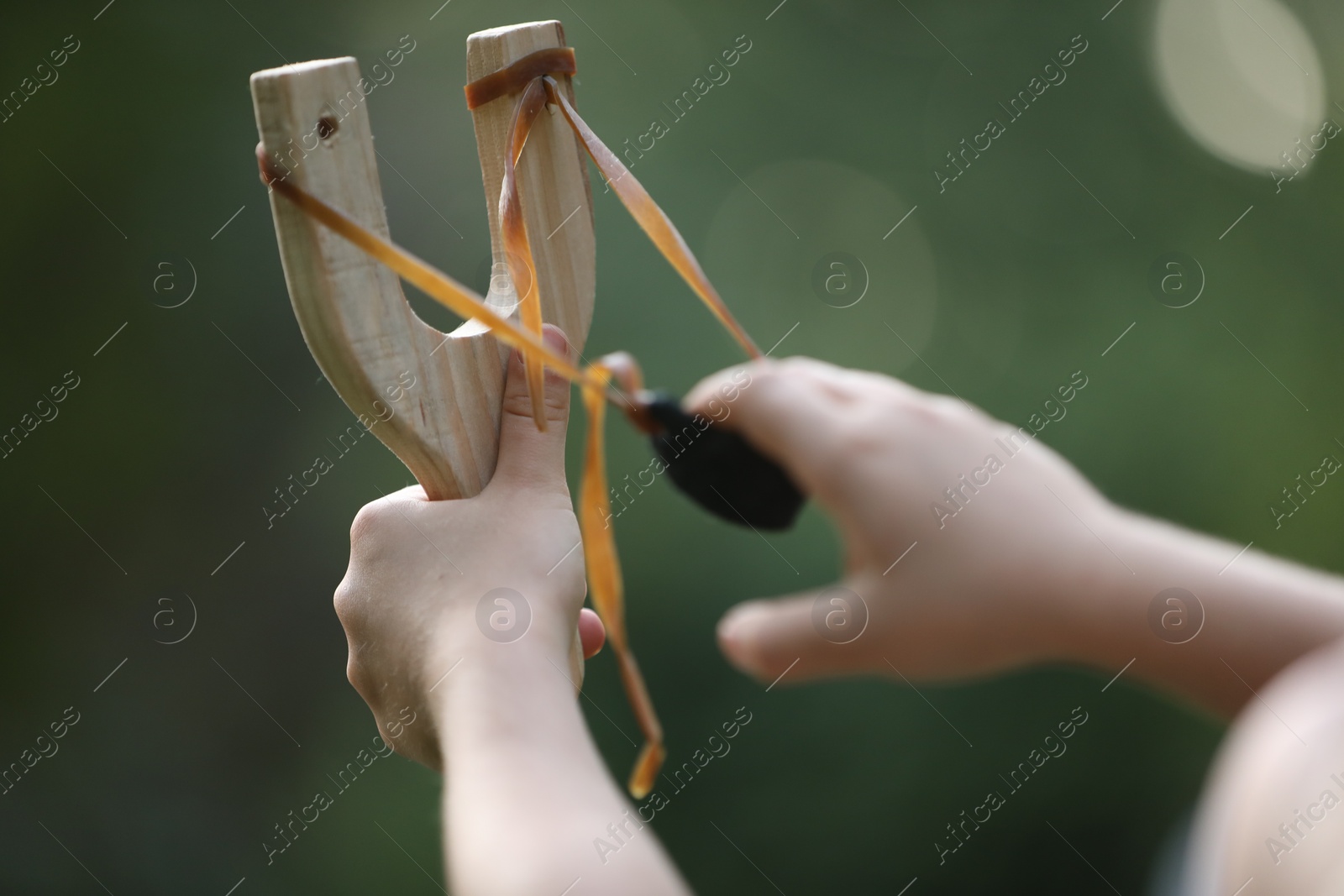 Photo of Little girl playing with slingshot outdoors, closeup