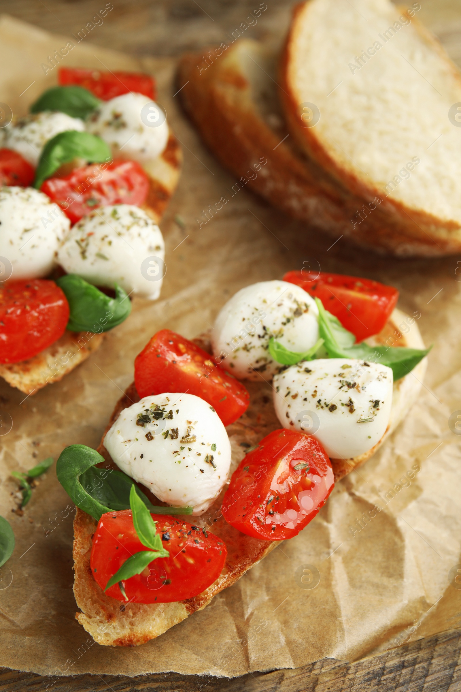 Photo of Delicious sandwiches with mozzarella, fresh tomatoes and basil on parchment