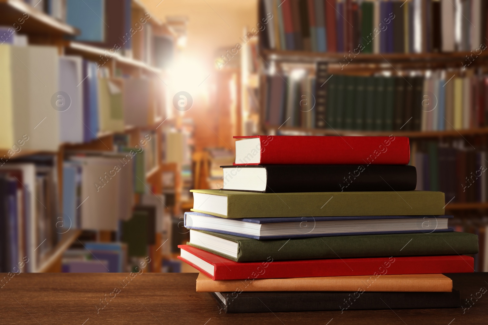 Image of Many stacked hardcover books on wooden table in library, space for text