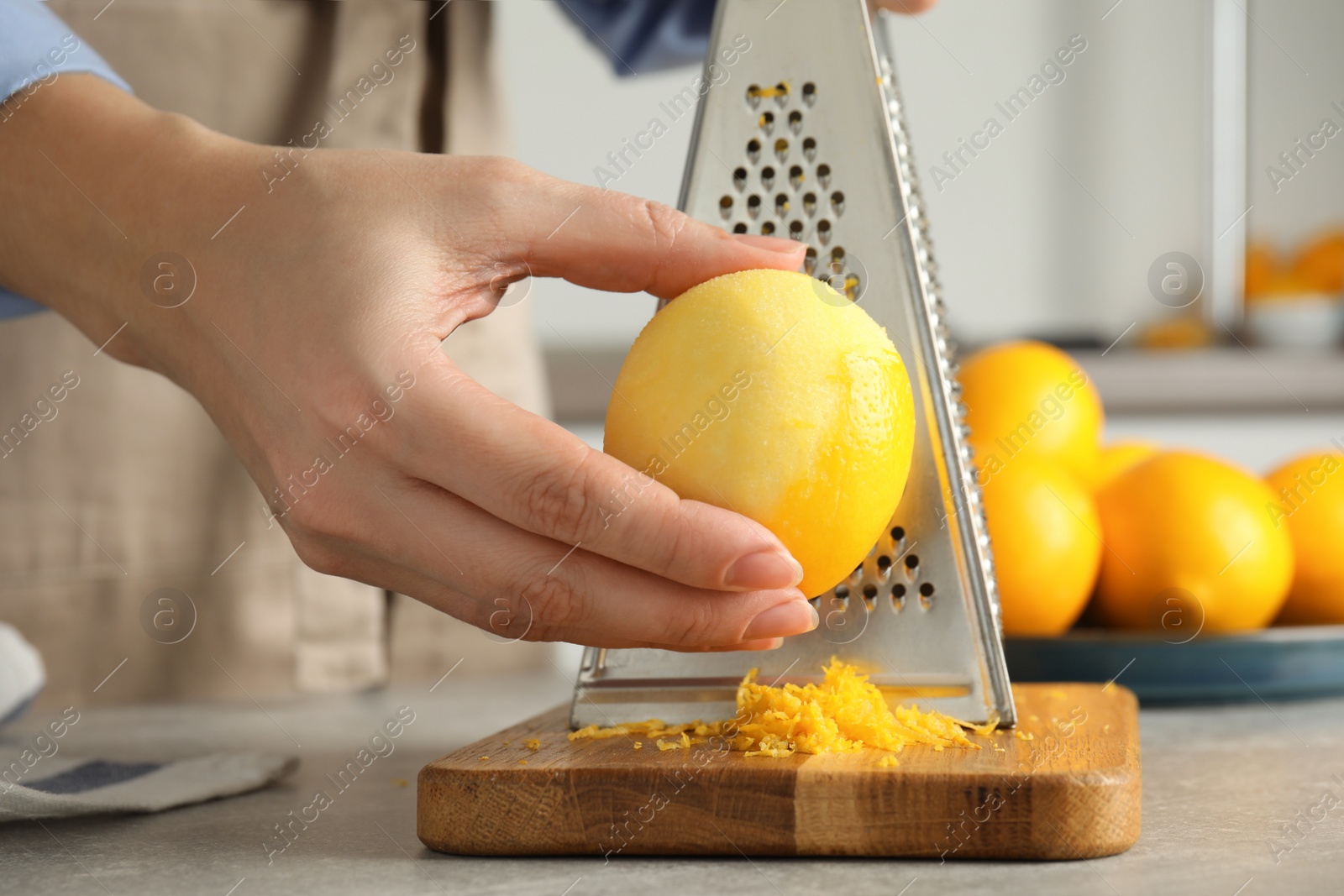 Photo of Woman zesting lemon at table indoors, closeup