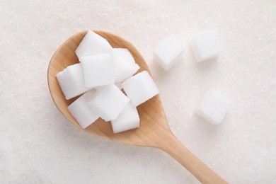 Different types of white sugar and spoon as background, top view