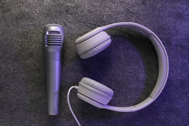 Photo of Microphone and headphones on grey textured background, flat lay. Sound recording and reinforcement