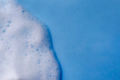 Photo of White foam on light blue background, top view. Space for text